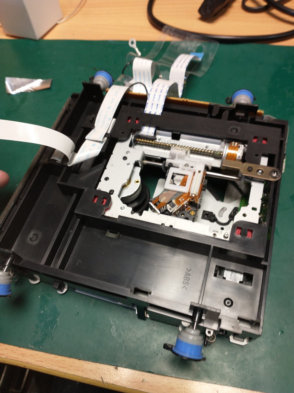 A CDJ deck opened up on the bench — the laser pickup assembly and mechanism exposed for service